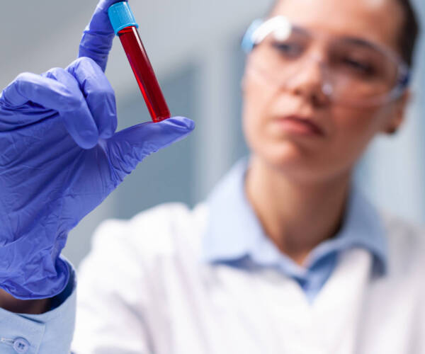 Specialist woman doctor looking at clinical vacutainer dna blood analyzing biology expertise. Chemist researcher discovering microbiology infection working in biochemistry medicine hospital laboratory